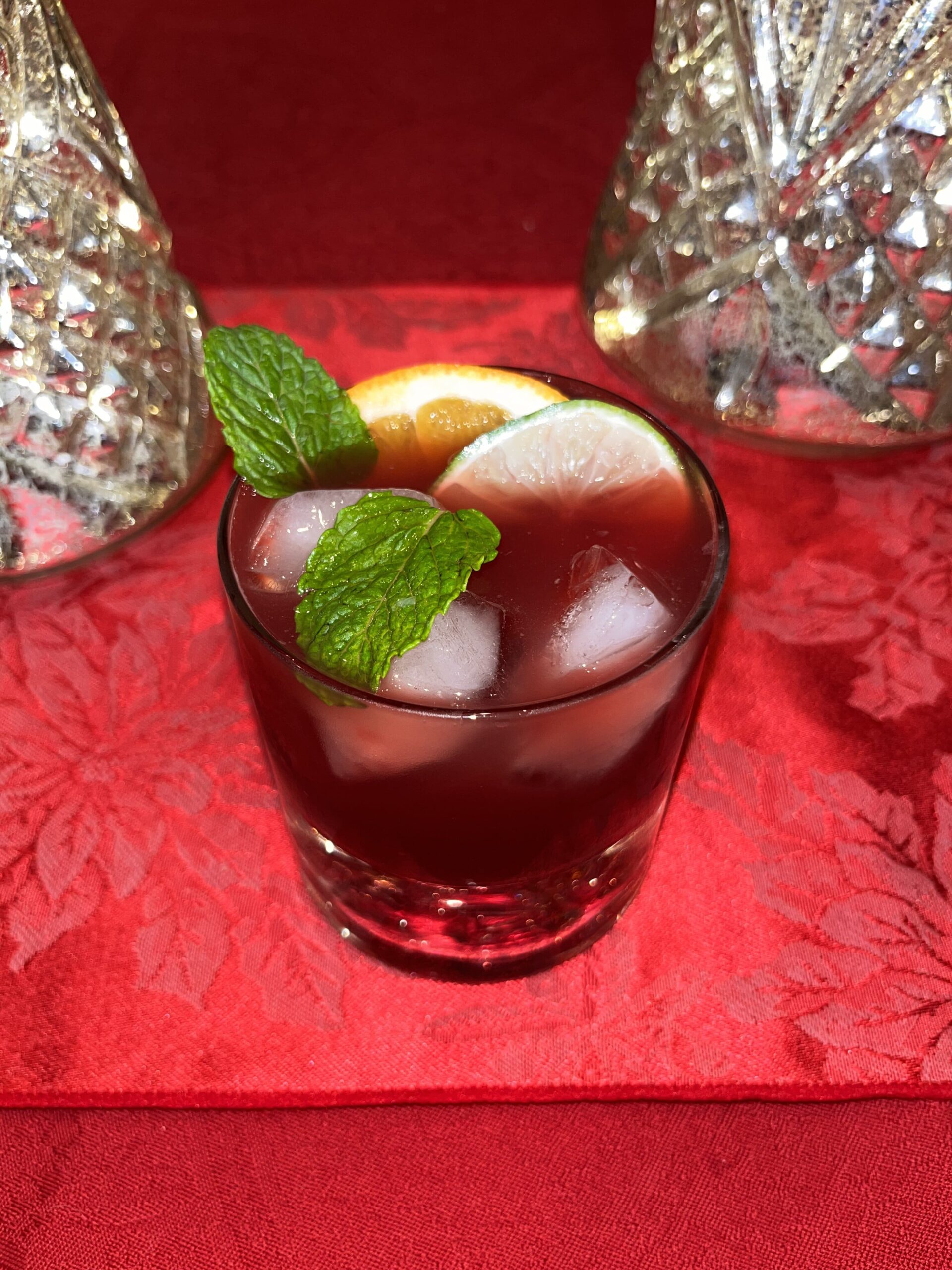 Festive holiday sangria with orange, lime, and mint garnishes, surrounded by colourful Christmas lights. This refreshing Christmas drink creates a warm, celebratory holiday atmosphere, perfect for festive gatherings and seasonal celebrations.